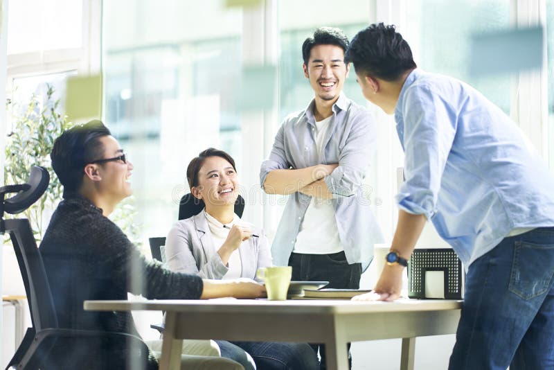 Group of four happy young asian corporate people teammates meeting discussing business in office. Group of four happy young asian corporate people teammates meeting discussing business in office